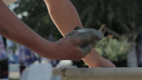 taking mud from the bucket and applying on the leg