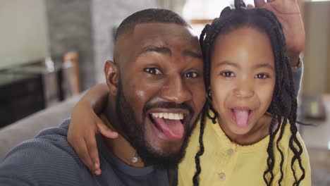 retrato de una feliz hija afroamericana y un padre haciendo tonterías y tomando selfies