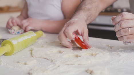 man using cookie mold on dough closeup of a man cutting dough with a cookie mold