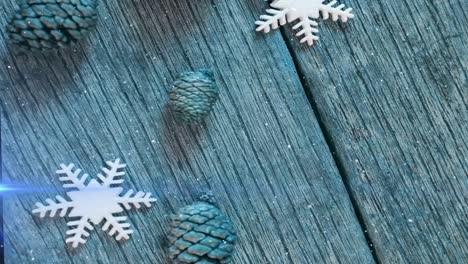 Animation-of-light-moving-over-pine-cones-and-snowflakes-on-wooden-surface