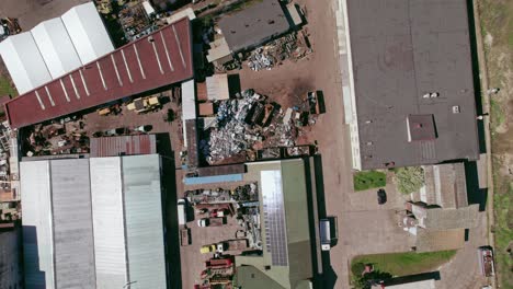 Flying-over,-looking-down-at-industrial-buildings,-factories-and-scrapyard