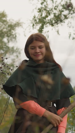 teenage girl with spear defeats enemy smiling with satisfaction. female warrior commands friends about further actions on blurred background low angle shot horizon tilts