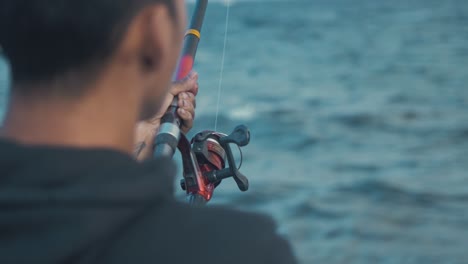 joven spin pescando en la orilla del mar por encima del hombro