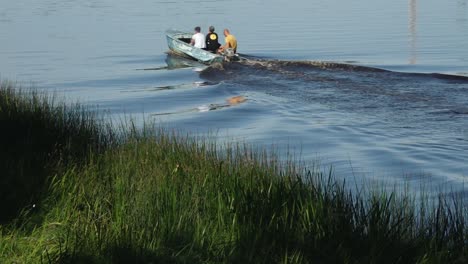 a group of fishermen is floating on a river in a motorboat, surrounded by calm waters and natural scenery. the scene reflects a peaceful outdoor activity. copy space available.