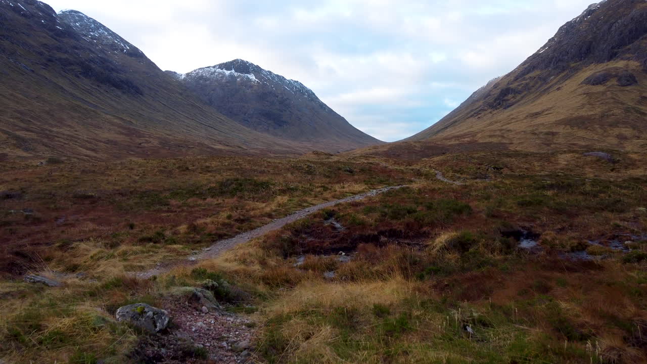 toma aérea de bajo nivel en movimiento lento del fondo del valle de las colinas y montañas en glencoe, escocia en gran bretaña