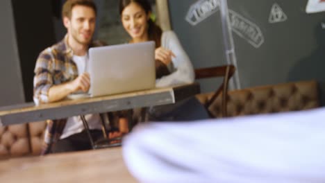 Couple-discussing-over-laptop-in-cafe-4k