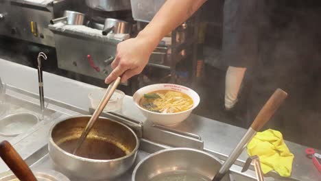 chef ladling soup into a noodle bowl