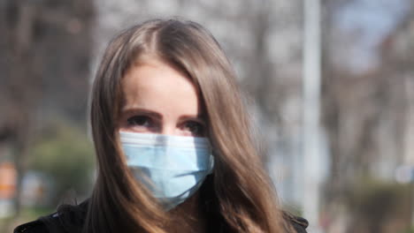 sad eyes behind face mask of young woman walking in city outdoor during covid-19 virus pandemic looking at camera, slow motion