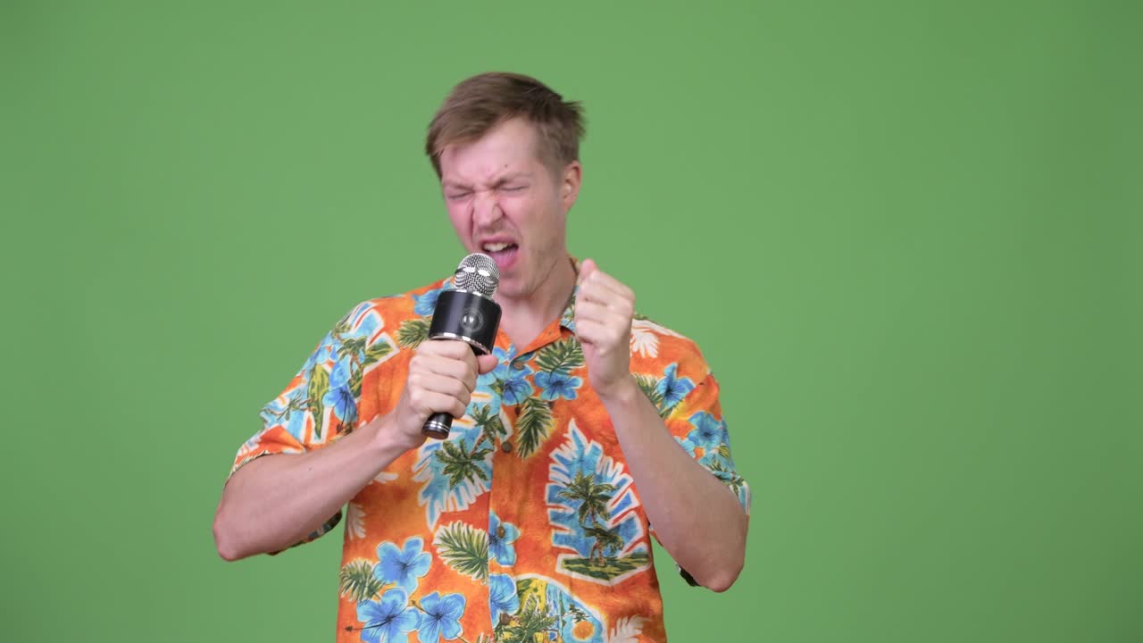 Young handsome tourist man singing on microphone