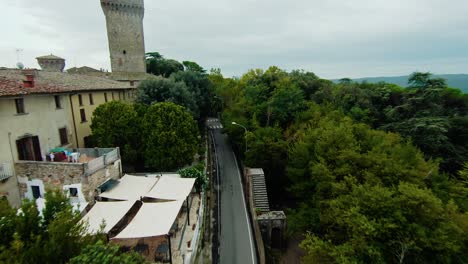 Carretera-Asfaltada-Y-Ciudad-Medieval-Con-La-Colegiata-En-Lucignano,-Provincia-De-Arezzo,-Toscana,-Italia