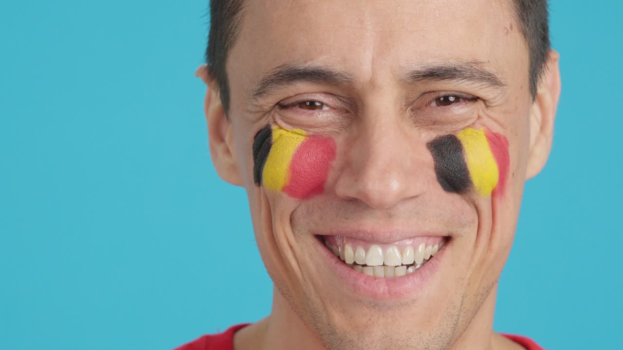 Man with a belgian flag painted on the face smiling