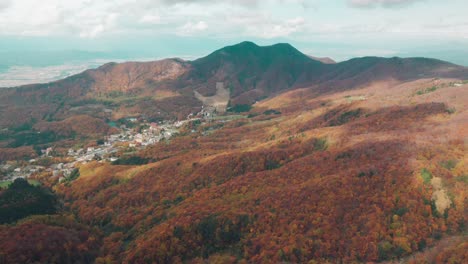 Espectaculares-Imágenes-De-Drones-De-Montañas-Japonesas-En-Colores-Otoñales-Con-Sombras-De-Nubes-Sobre-El-Pueblo,-Zaoonsen-En-Japón,-Toma-Aérea