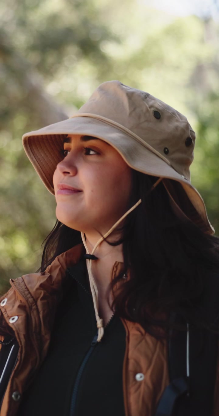 Giovane donna con cappello da escursionismo che si gode la natura nel bosco