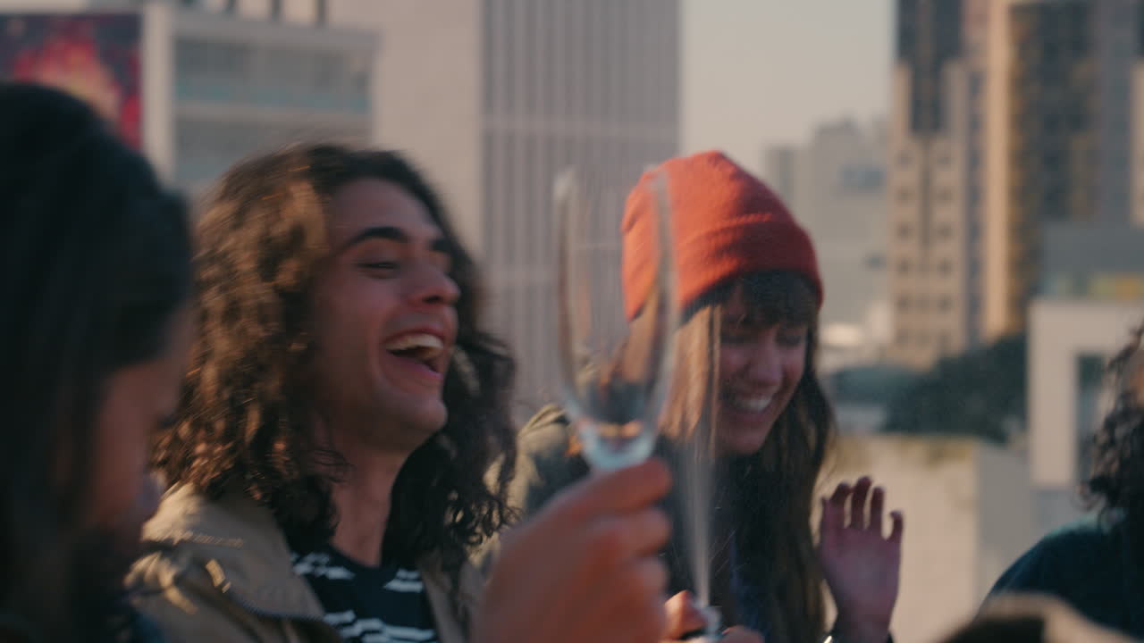 joven haciendo estallar corcho vertiendo champán feliz grupo de amigos celebrando en la azotea divirtiéndose celebrando las vacaciones de verano al atardecer