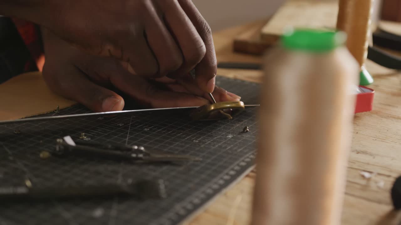 cerca de las manos de un artesano afroamericano preparando un cinturón en un taller de cuero