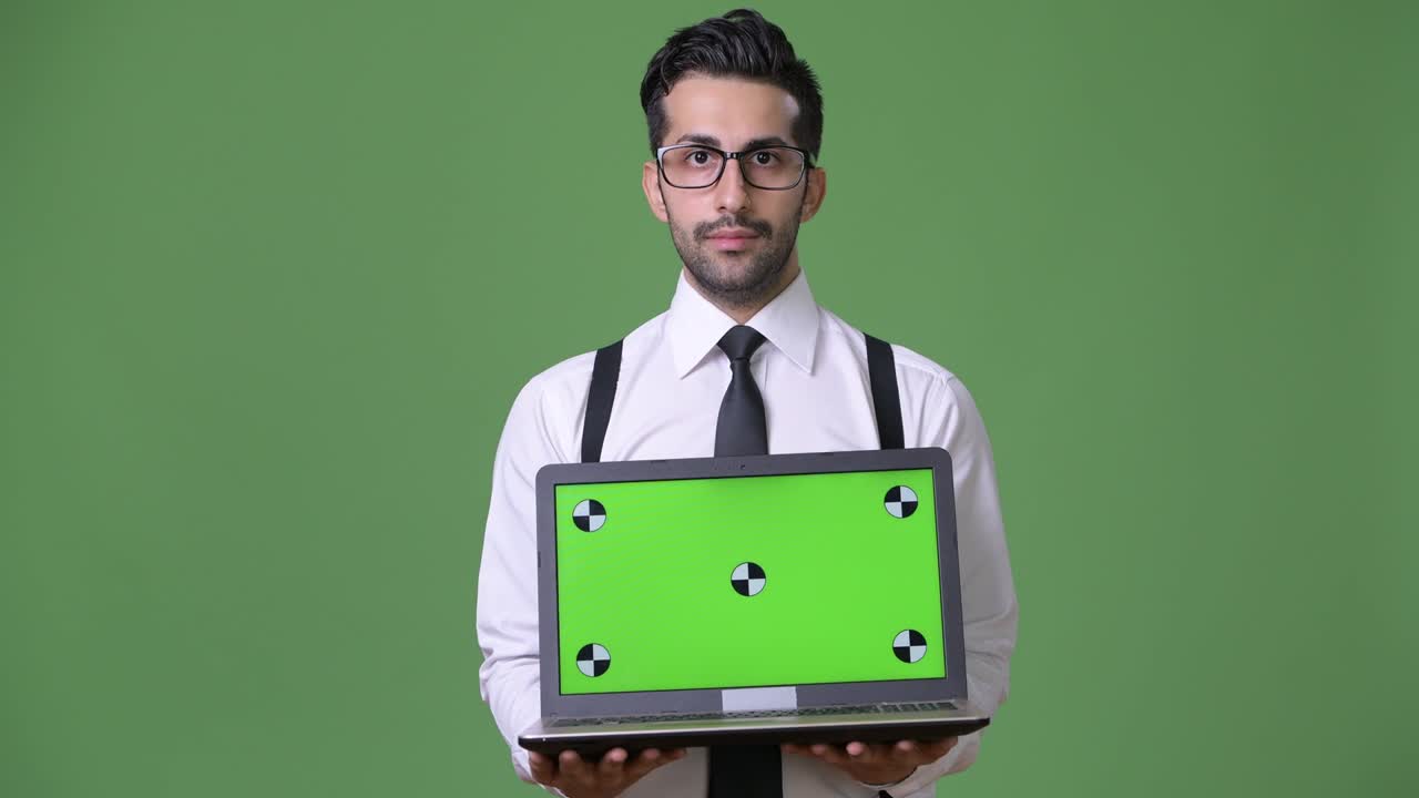 joven empresario persa barbudo y guapo contra un fondo verde