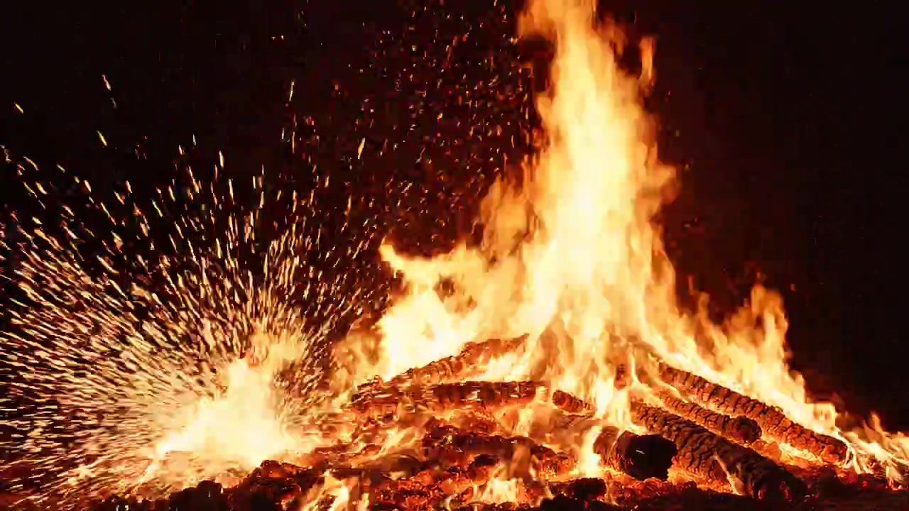 Massive bonfire with blazing flames and glowing sparks at night