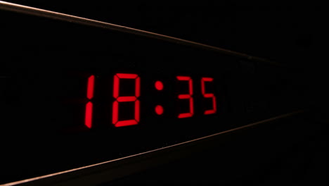 Red-digital-display-clock-with-24-hour-time-shows-time-flying-by,-timelapse