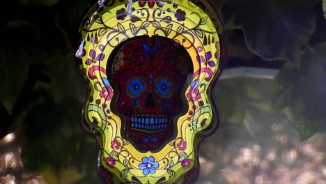 Hypnotic-metal-sugar-skull-decorative-spinning-colourful-garden-ornament-hanging-from-tree