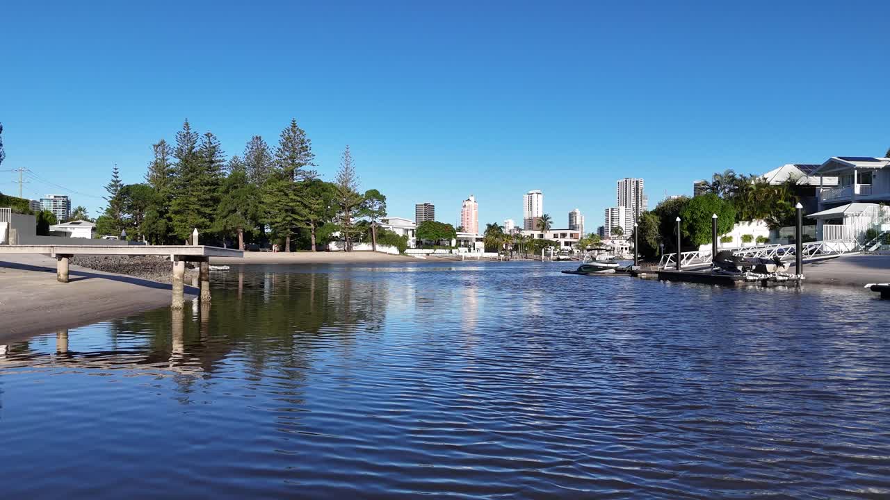 Aerial view of serene river, luxury homes, and clear skies in Gold Coast, Australia. Captured with smooth drone movement and natural lighting