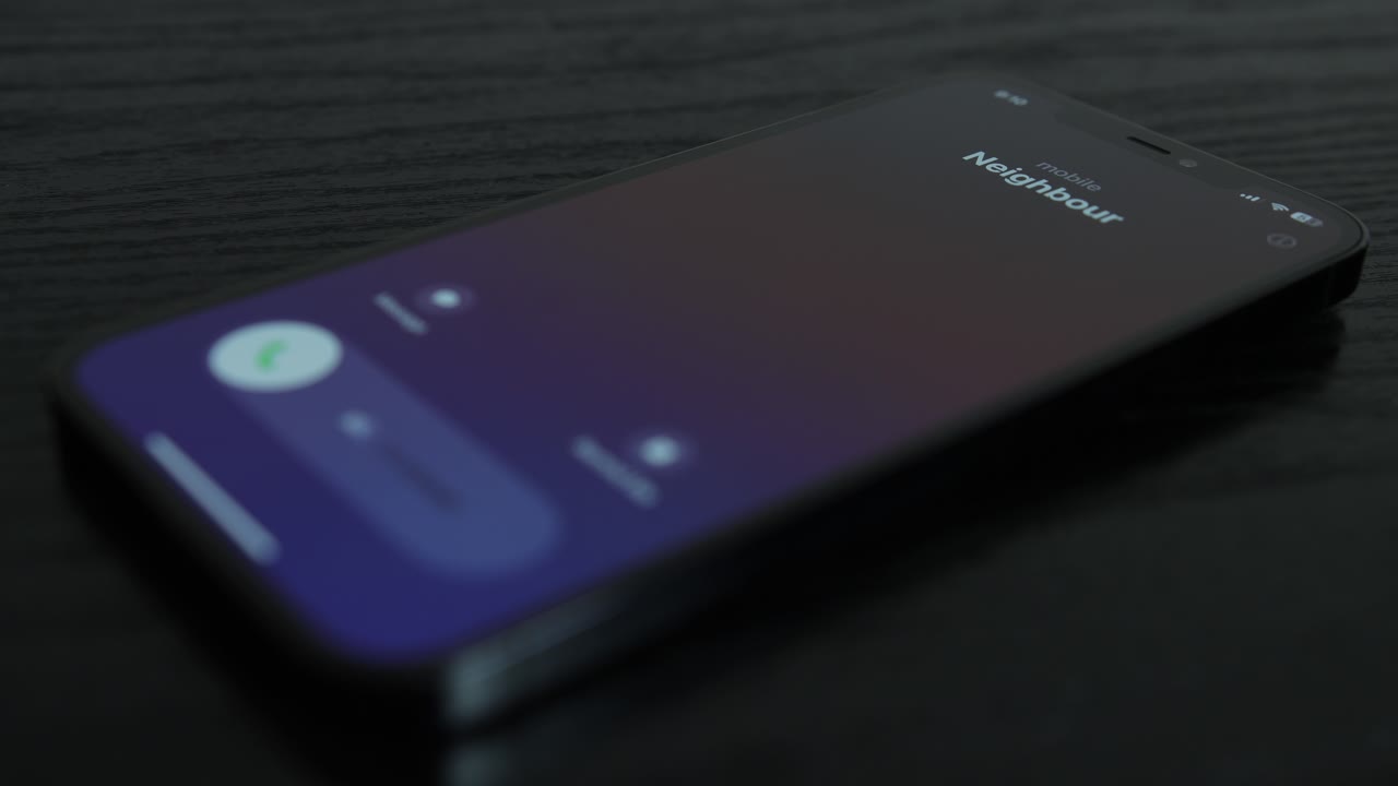 fotografía de primer plano de un iphone recibiendo una llamada de un vecino en una mesa de madera negra