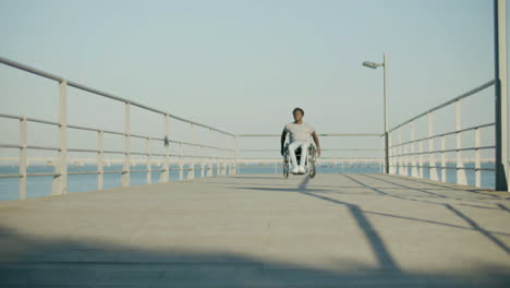 front view shot of black man riding wheelchair at seafront