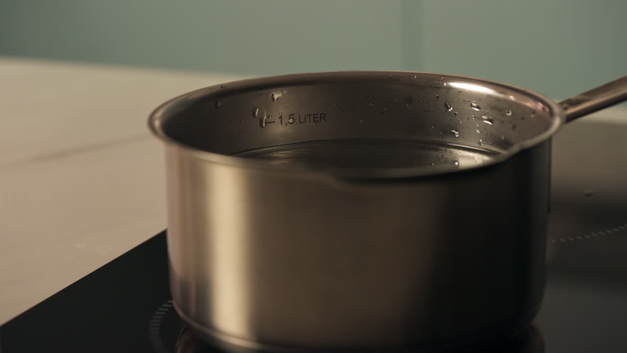 Pentola in acciaio inossidabile riempita con acqua fumante per far bollire le uova - Preparativi di Pasqua. Primo piano.