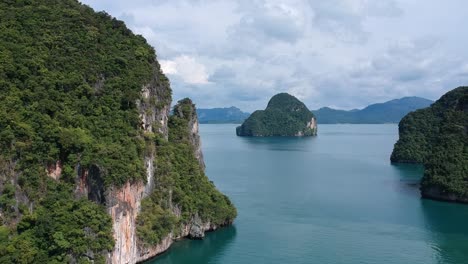 drone footage of islands in thailand with limestone rock formation sticking out of the water and the ocean in background-7