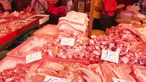 various cuts of meat displayed at a busy market