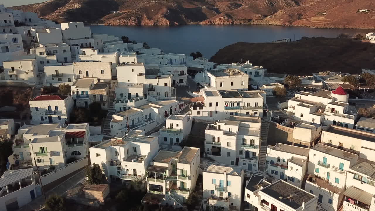 Greece, Astypalea Island, Drone Footage starting from iconic Astypalea wind mills and footage slowly moves towards to the beautiful old castle early in the morning, no people half sunny half shade.
