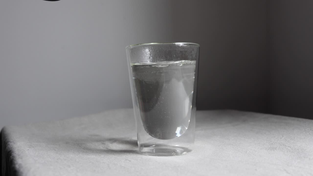 Versamento di acqua calda da un bollitore in un bicchiere trasparente.