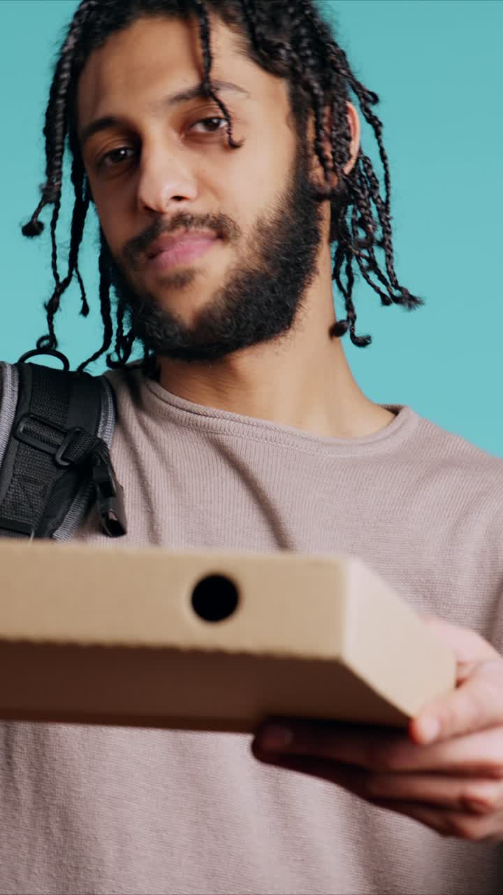 Vertical video Portrait of BIPOC courier delivering pizza order to client, camera background