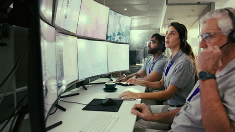 un equipo de personas que trabajan en una oficina con múltiples pantallas de computadora