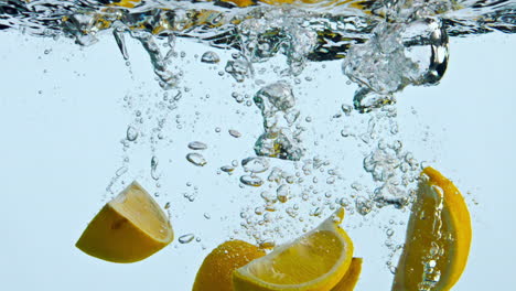 piezas de naranja sumergidas en agua sobre fondo blanco. cuñas de cítricos salpicando líquido