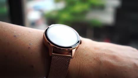 a close-up view of a stylish smartwatch on a wrist, showcasing its sophisticated design and sleek metal band against a blurred outdoor background