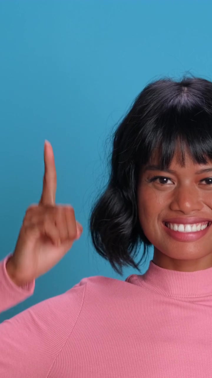 Happy southeast asian woman pointing her index finger upwards on blue studio