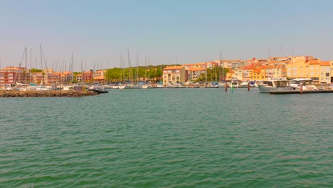 zoom in shot of waterfront residential buildings and moored boats at cap d'agde marina on a summer day