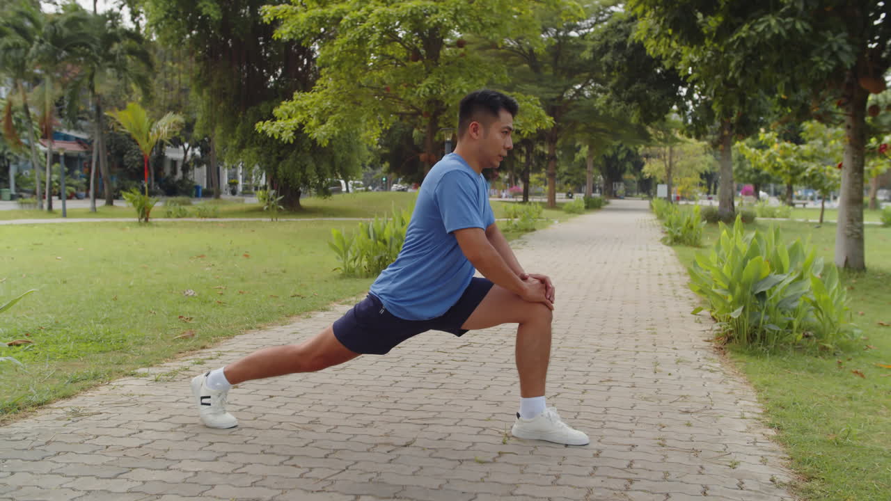 Asiatischer Sportler übt Ausfallschritte im örtlichen Park