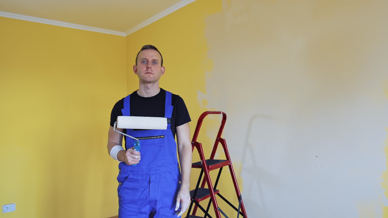 Man painting with roller. Workman in the uniforms painting the walls with paint roller