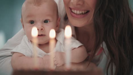 Mamá-Con-Bebé-Soplando-Vela-De-Cumpleaños.-Mujer-Con-Niño-Soplando-Velas-En-El-Pastel