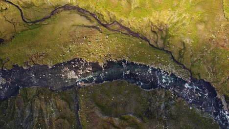Top-down drone aerial view of a mountain river winding through remote Norwegian highland terrain