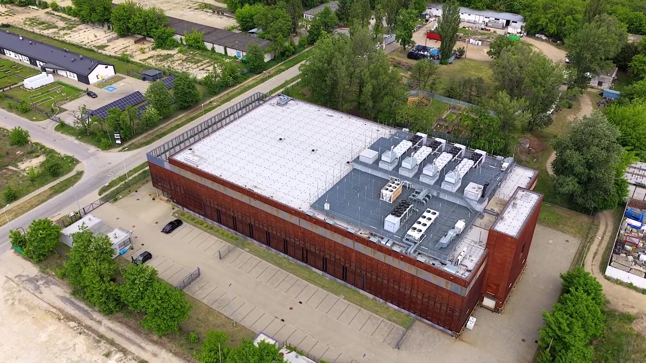 Imágenes de dron que muestran un gran y moderno edificio de centro de datos de IA. La fachada de metal oxidado y los sistemas de refrigeración en la azotea destacan su infraestructura avanzada