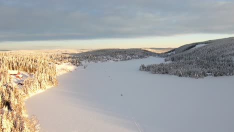 Beautiful-frozen-lake-with-skiers-and-mountains-in-the-sunset-in-Norway