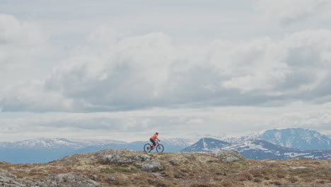 epic mountain biking adventure above the fjords near sogndal, norway. rider tackles rugged trails surrounded by dramatic cliffs, lush green hills, and stunning nordic scenery