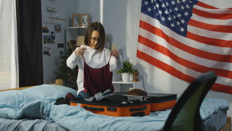 teenage girl packing a suitcase in her bedroom
