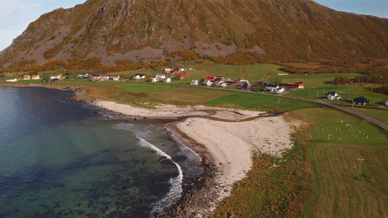 Lush coastline with a scenic view of mountains and colorful homes along a winding road