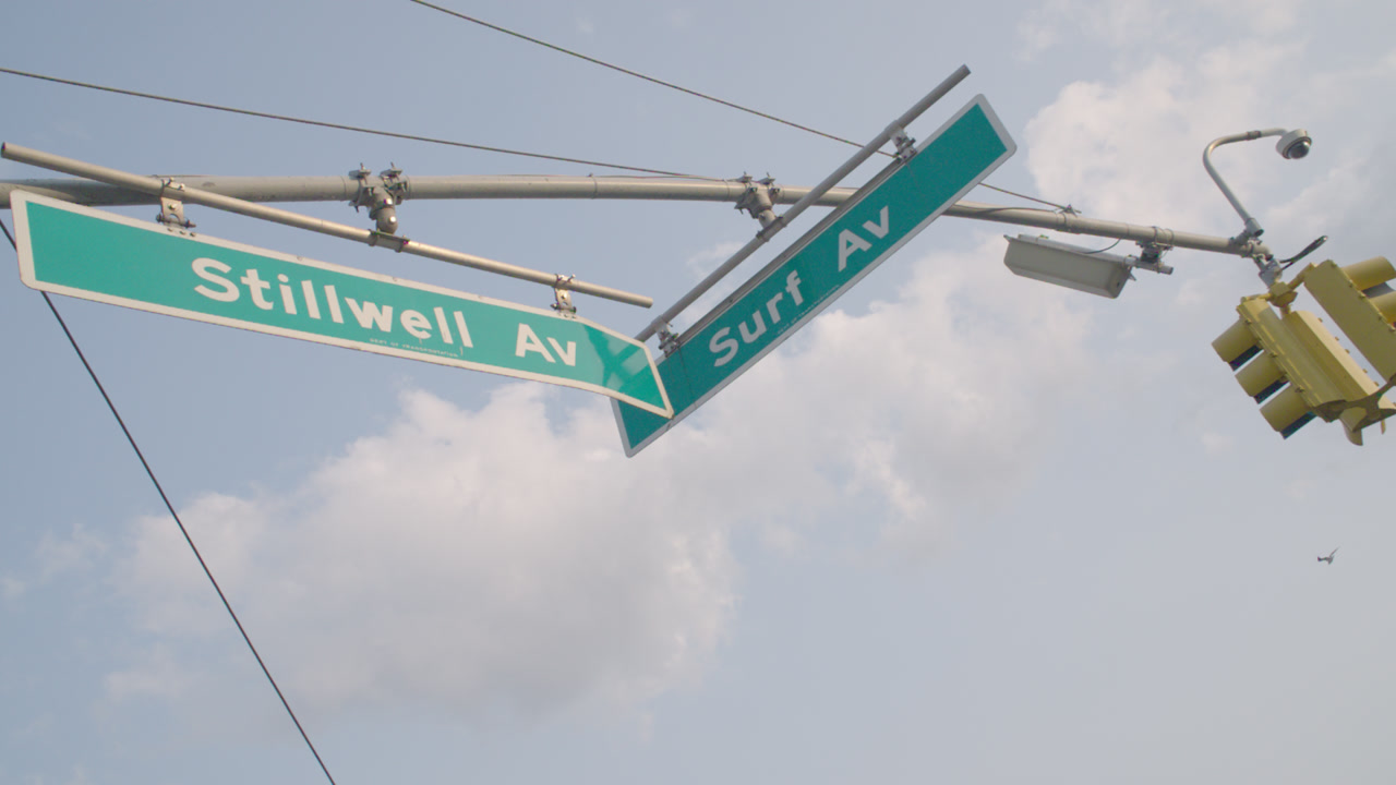 Establishing shot of street signs in Coney Island. Shot at the intersection of Stillwell Avenue and Surf Avenue in Brooklyn.