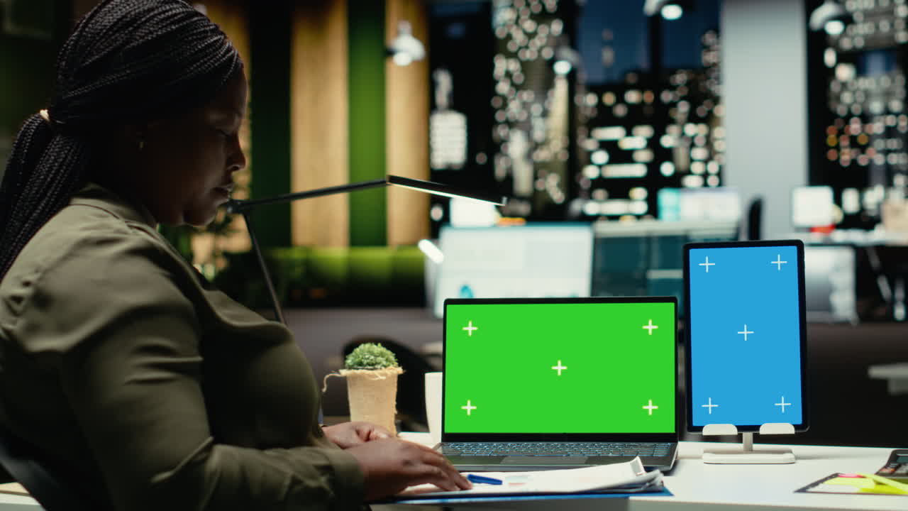 Green screen and vertical blue screen on two devices next to worker