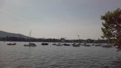 zurich, switzerland - june 28, 2019: boats on lake zurich at sunset, buildings of the city of zurich