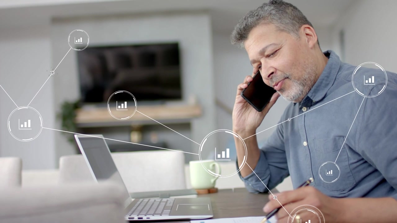 Man taking business call and reviewing docs at home, animated network charts linking laptop and mug